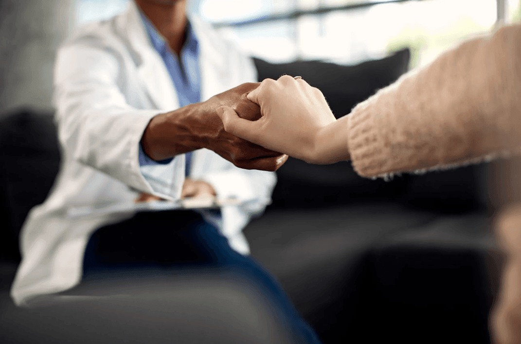 Profissional de saúde segurando as mãos de uma pessoa enlutada, simbolizando apoio psicológico credenciado e acompanhamento emocional oferecido pela Além Fúnebre nas regiões de Sintra, Cascais, Oeiras, Amadora e Loures.