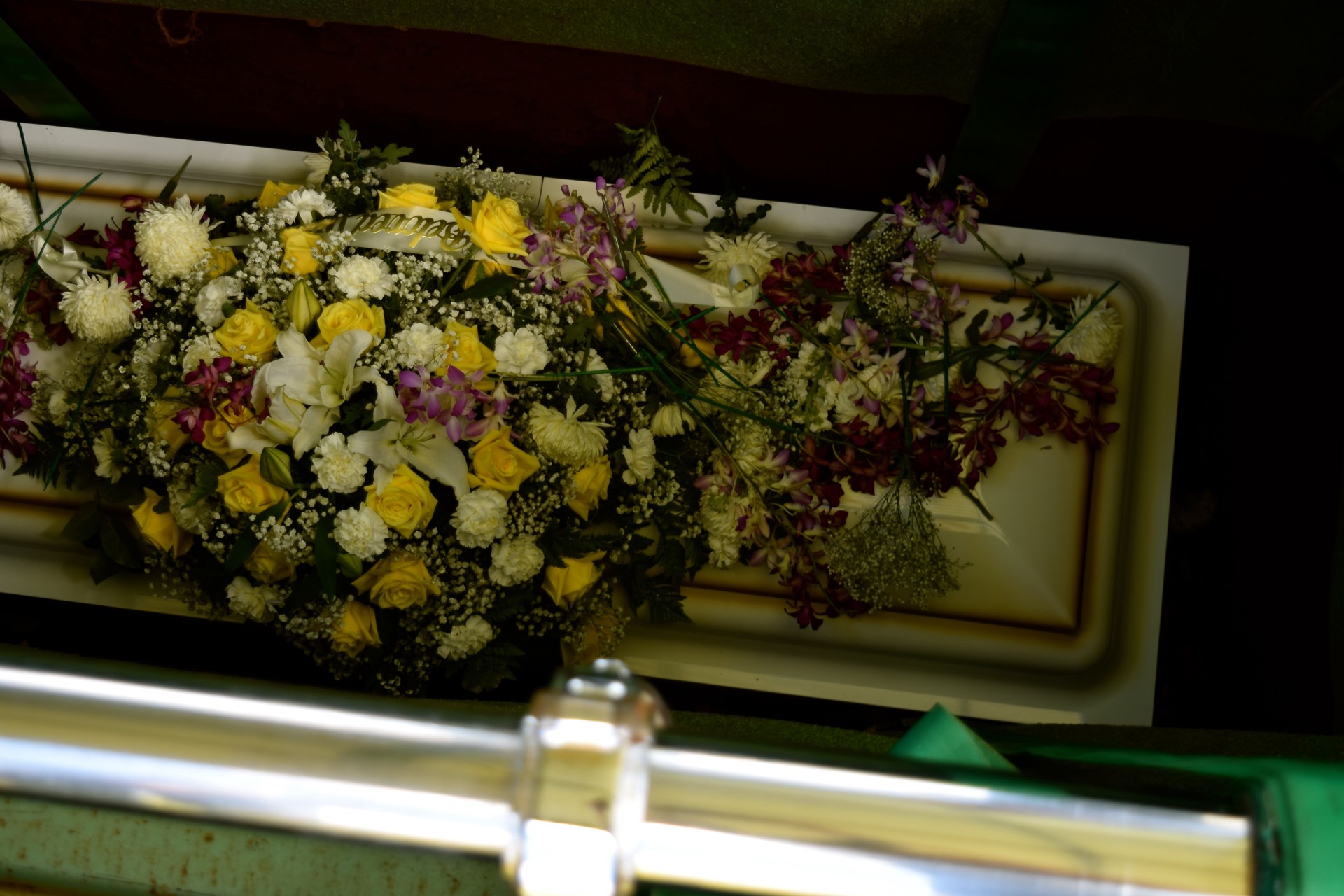 Arranjo de flores sobre caixão branco durante cerimónia fúnebre, representando homenagem personalizada organizada pela Além Fúnebre em Sintra, Cascais, Oeiras, Amadora e Loures.