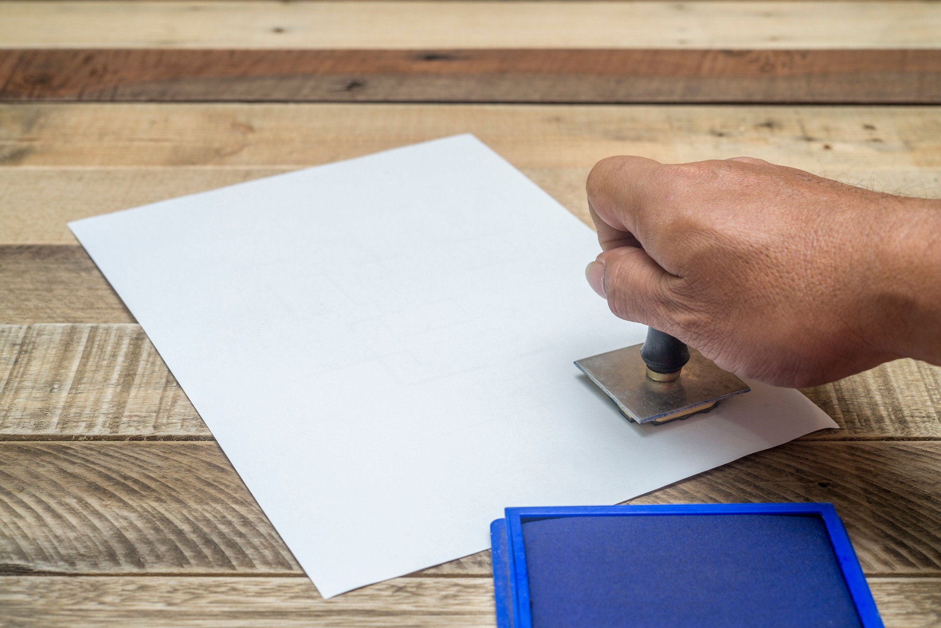 Mão carimbando documentos oficiais – Serviço de documentação funerária para tratar de burocracias pela família.